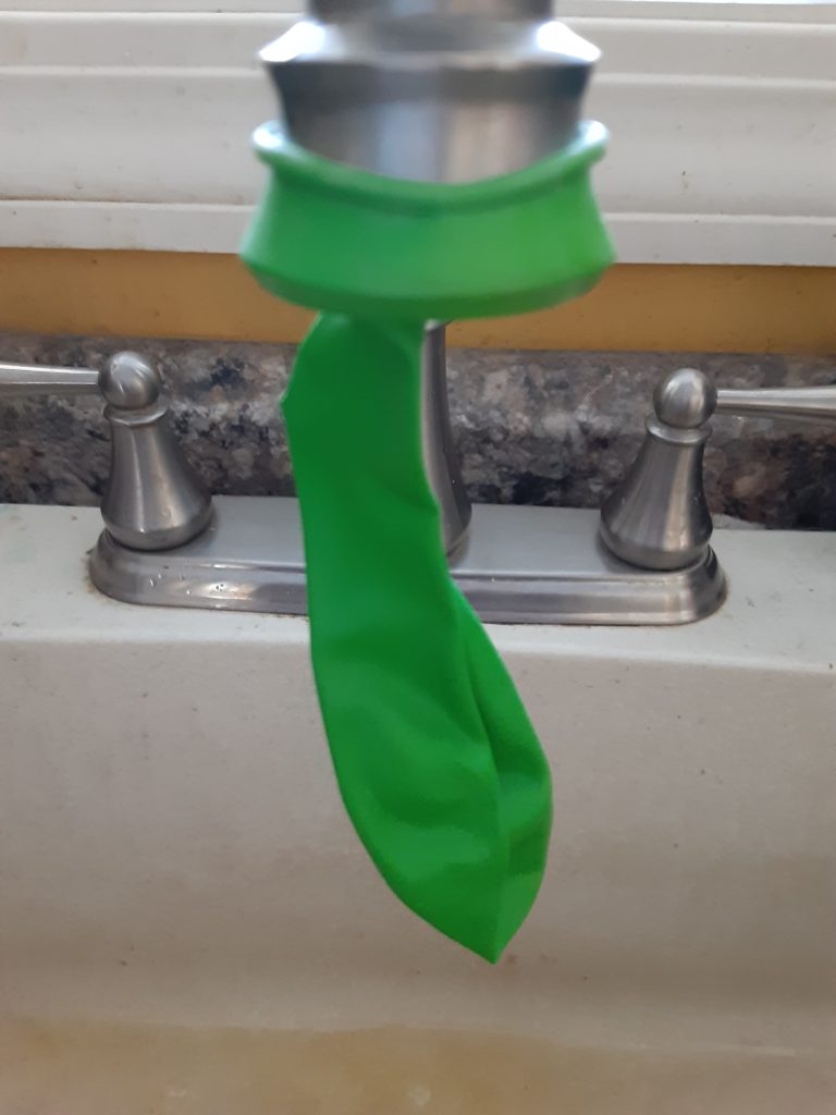 attaching the balloon to the faucet to begin filling it with water