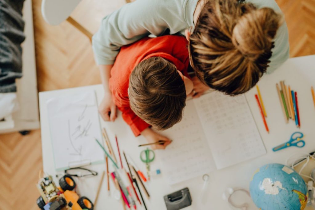 boy at home working with his mother in a workbook is one type of homeschool day