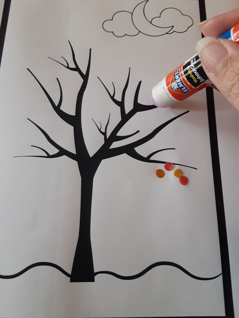 gluing punched out leaves onto fall tree worksheet